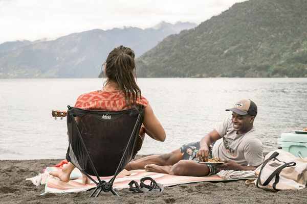 Girl sitting on beach chair and guys is lying on beach